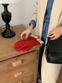Detail of red knit touchscreen gloves with ribbed cream cuffs on a vintage wooden surface - Red