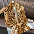 Detail of leopard print scarf with soft frayed edges on a brown leather background - 180cm x 90cm / Camel
