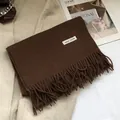 Detailansicht des Etiketts aus 100% Wolle und der weichen Fransen am braunen Schal - 180*30cm / Rötliches Braun