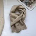 Detail of 100% Australian wool scarf featuring a leather label and soft knitted texture - Cream Rice