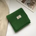 Dettaglio sciarpa verde in 100% pura lana con trama a maglia a coste ed etichetta - Verde Natale