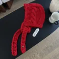 Detail of red hand-knitted bonnet with cable stitch texture and heart-shaped charms - Red