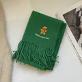 Detail of green Christmas scarf featuring gingerbread man embroidery and soft fringe trim - Green Gingerbread Man