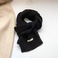 Detailed texture of black knit 100% wool scarf showing authentic material label - Black