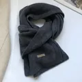 Detailed macro view of 100% pure wool scarf texture with dark grey woven fabric labels - Gray