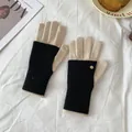 Detail of black rib-knit winter gloves featuring cream fingertips and small gold metal button - Black and Beige