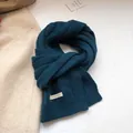 Dettaglio della sciarpa in lana verde petrolio con etichetta 100% lana e maglia a trecce - Blu navy