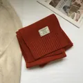Detail shot of 100% Australian wool scarf featuring ribbed knit hem and woven label - Orange Red