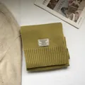 Detail view of mustard green 100% Australian wool scarf with fine knit texture and brand tag - Mustard Yellow