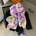 Blumenschal mit lila und rosa Blüten und dunklen Quasten auf einem schwarzen Pullover - Lebendiger Blumendruck