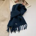 Close-up of navy blue wool knit scarf with fine tassel fringes and silver metal logo tag - Navy Blue
