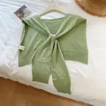 Close-up of light green knitted shawl with washing label on a white bed sheet - Green