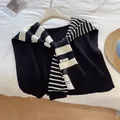 Detailed close-up of a black and white striped knitted shawl with high-quality brand tag - Black