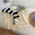 Detail of knitted striped shawl over a beige vest with brand labels on a hanger - White