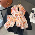 Elegant floral chiffon scarf with fine tassels draped over a black top on a desk - 180x90cm / Khaki