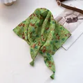 Detailansicht eines grünen Baumwollschals mit Hirschprint und Eckquasten-Verzierung - Grünes Pony
