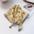 Close-up of yellow horse print square scarf featuring decorative tassels on corners - Yellow