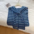 Primer plano de chal de punto a rayas azul marino y blanco con detalle de etiqueta - Verde azulado
