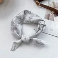 Detalle de pañuelo satinado blanco con estampado floral y un nudo de estilo elegante - Blanco