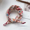Détail d'un foulard en coton noué avec un motif floral de marguerites multicolores - Marguerite Beige
