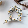 Vista de detalle del pañuelo de seda blanco con estampado floral amarillo y nudo elegante - Blanco con Girasoles Amarillos
