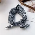 Nahaufnahme eines geblümten dunkelblauen Baumwolltuchs, geknotet neben einer Ledertasche - Navy Blumenmuster