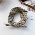 Detail eines floralen Baumwollstirnbandes mit Hasenohrknoten auf hellem Grund - Beige Blumenmuster
