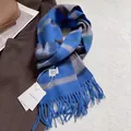 Gros plan détaillé de l'écharpe en laine à rayures bleues et marron avec de longues franges - 180x30cm / Bleu à Rayures