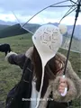 Outdoor shot of a white wool knit trapper hat featuring hollow patterns and pompom - Ivory