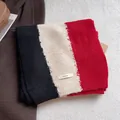 Detail of three-color knit scarf texture with BOWLOW woven label on soft white fabric - Black Beige Red