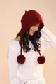 Detail of dark red knit wool trapper hat with fluffy pom-poms and warm ear flaps - Red