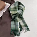 Détail de l'écharpe en laine à carreaux verts avec franges sur un manteau brun - 180x30cm / Damier Vert