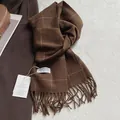 Détail macro de l'écharpe en laine à carreaux marron foncé avec franges et étiquette de marque - 180x30cm / Carreaux Brun Cacao