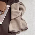Detail of wool blend knitted scarf featuring gold metal logo and brown stripe accents - Oatmeal Beige