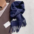 Vue détaillée d'une écharpe en laine à carreaux bleu foncé avec franges sur un manteau brun - 180x30cm / Carreaux Bleu Marine