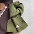 Detail of moss green wool blend scarf showing the texture and brand label on white fur - Green