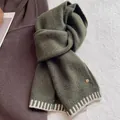 Detail of wool blend knit scarf in dark green with white stripes and a gold logo tag - Army Green