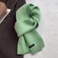 Detail of light green 100% wool scarf showing knit texture and premium material label - Water Green