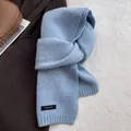 Detailed close-up of blue 100% wool knitted scarf with flecked texture and sewn label - Azure