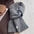 Nahaufnahme eines dicken dunkelgrauen Wollstrickschals mit weicher Textur und Etikett - Grau