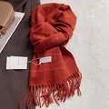 Détail d'une écharpe en laine à carreaux orange avec glands faits main et étiquette tissée - 180x30cm / Carreaux Orange