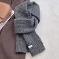 Detailed view of dark grey chunky wool blend knit scarf with white woven brand label - Dark Gray