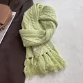 Close-up of 100% wool knit scarf featuring cable patterns and soft fringe detail - Apple Green