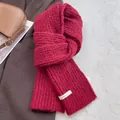 Close-up of chunky burgundy wool scarf with knit texture and BOWLOW brand label - Red