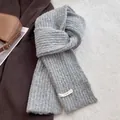 Detailed close-up of a grey ribbed wool knit scarf with a white rectangular brand label - Light Gray