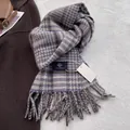 Detailed close-up of wool blend plaid scarf with blue fringe and woven brand label - Purple