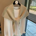 Detail of light beige knitted shawl with soft texture and brand label on a white top - Apricot