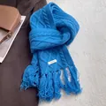 Detailed macro view of 100% wool scarf featuring cable knit pattern and fringed edges - Blue