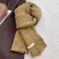 Close-up of mustard yellow chunky knit wool scarf texture with brand woven label - Yellow