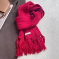 Detail of red cable knit wool scarf showing thick weave texture and soft tassels - Red